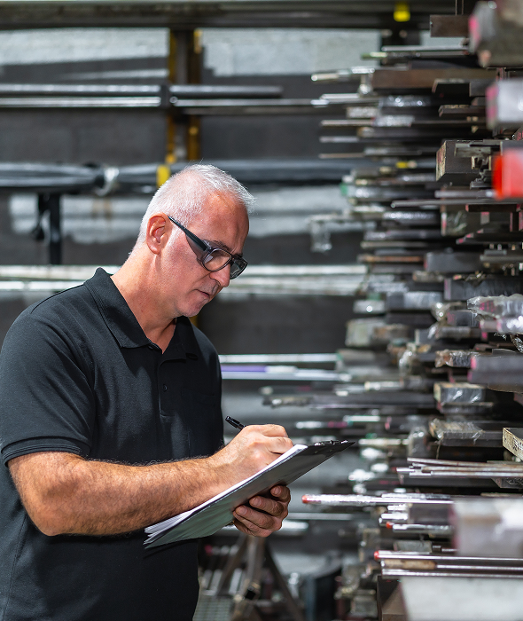 Man with clipboard in industrial warehouse.