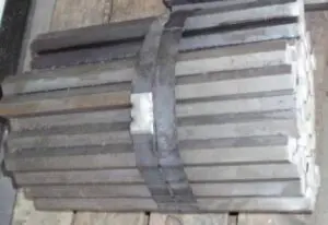 Stacked metal bars on wooden surface.
