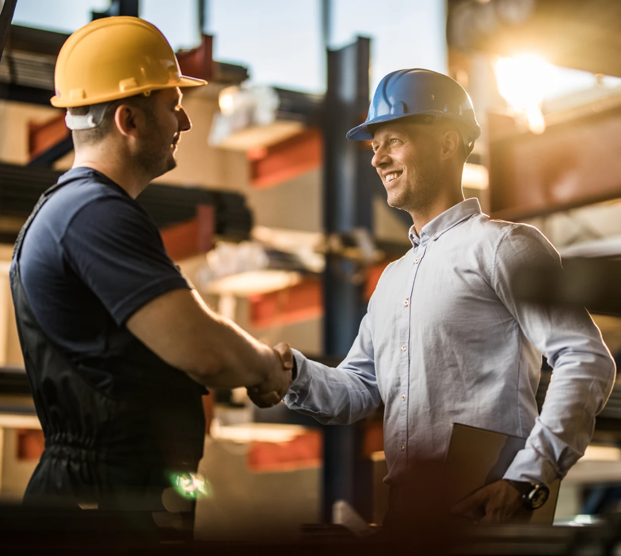 Two men in hard hats shaking hands.