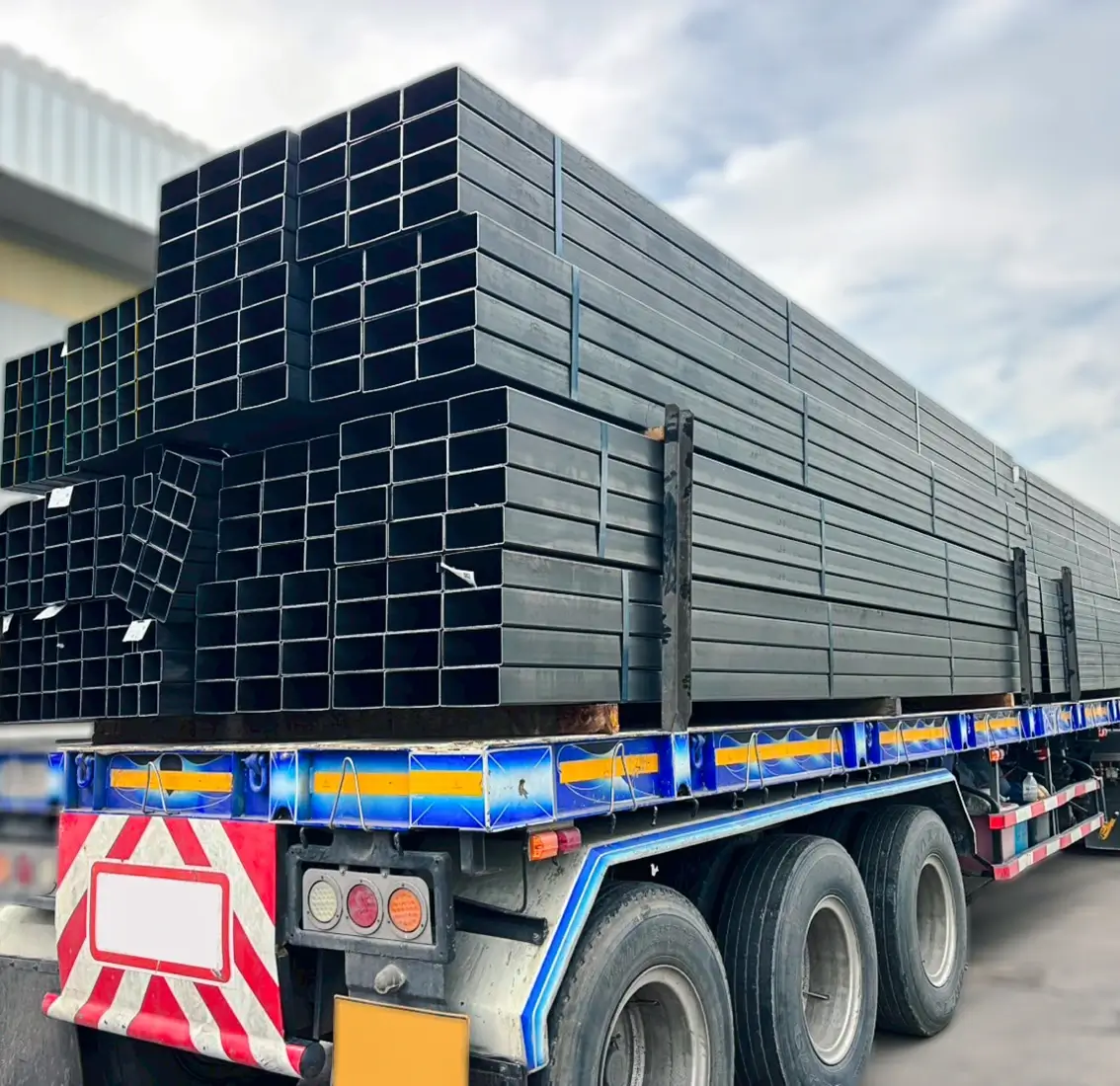 Truck transporting stacked metal pipes.