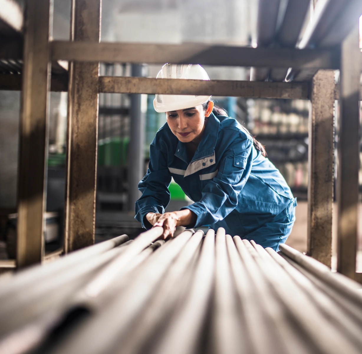Worker inspecting pipes in industrial setting.